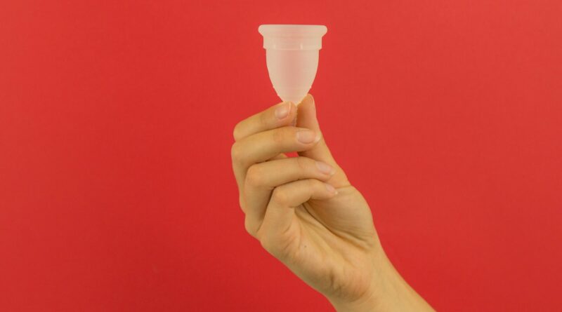 Hand holding menstrual cup with a red background