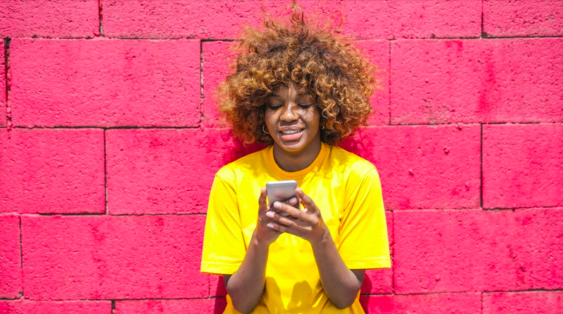 Young woman using phone, smiling