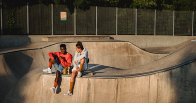 Two young men sitting with skateboards in skate park