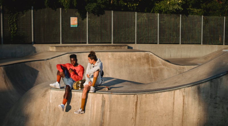 Two young men sitting with skateboards in skate park