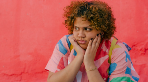 Young person looking unhappy against a pink wall background