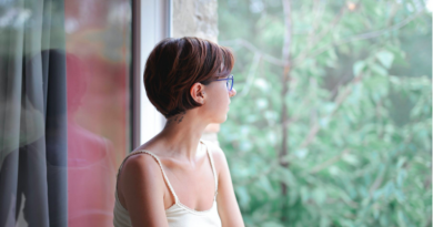 Young woman looking through window pensively