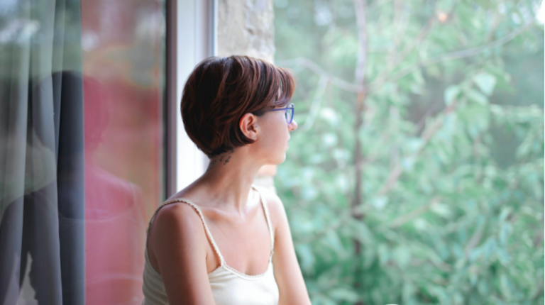 Young woman looking through window pensively