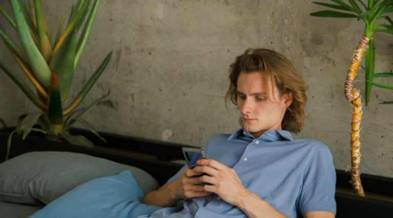 Man using phone reclining on sofa