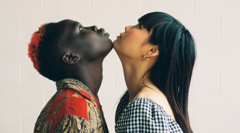 two people chin-to-chin looking upwards against a white-grey wall