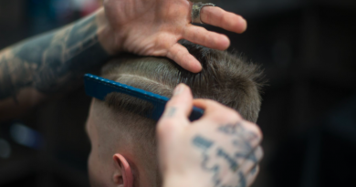 A haircut taking place in a barbers, head of the client and hands of the barber using a comb on the client's hair